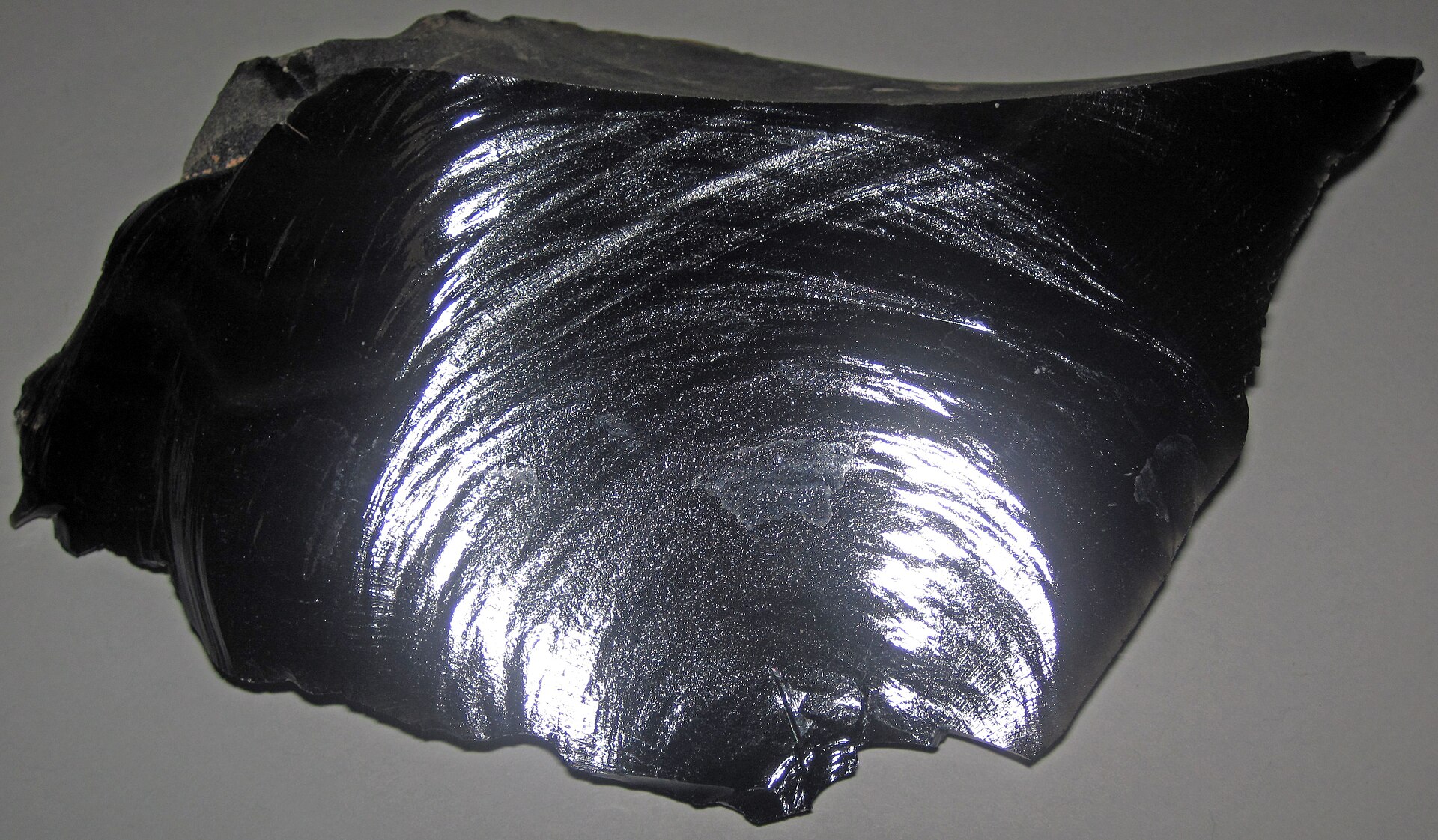 Obsidian mineral specimen — (~13.7 centimeters across at its widest) Igneous rocks form by the cooling & crystallization of hot,