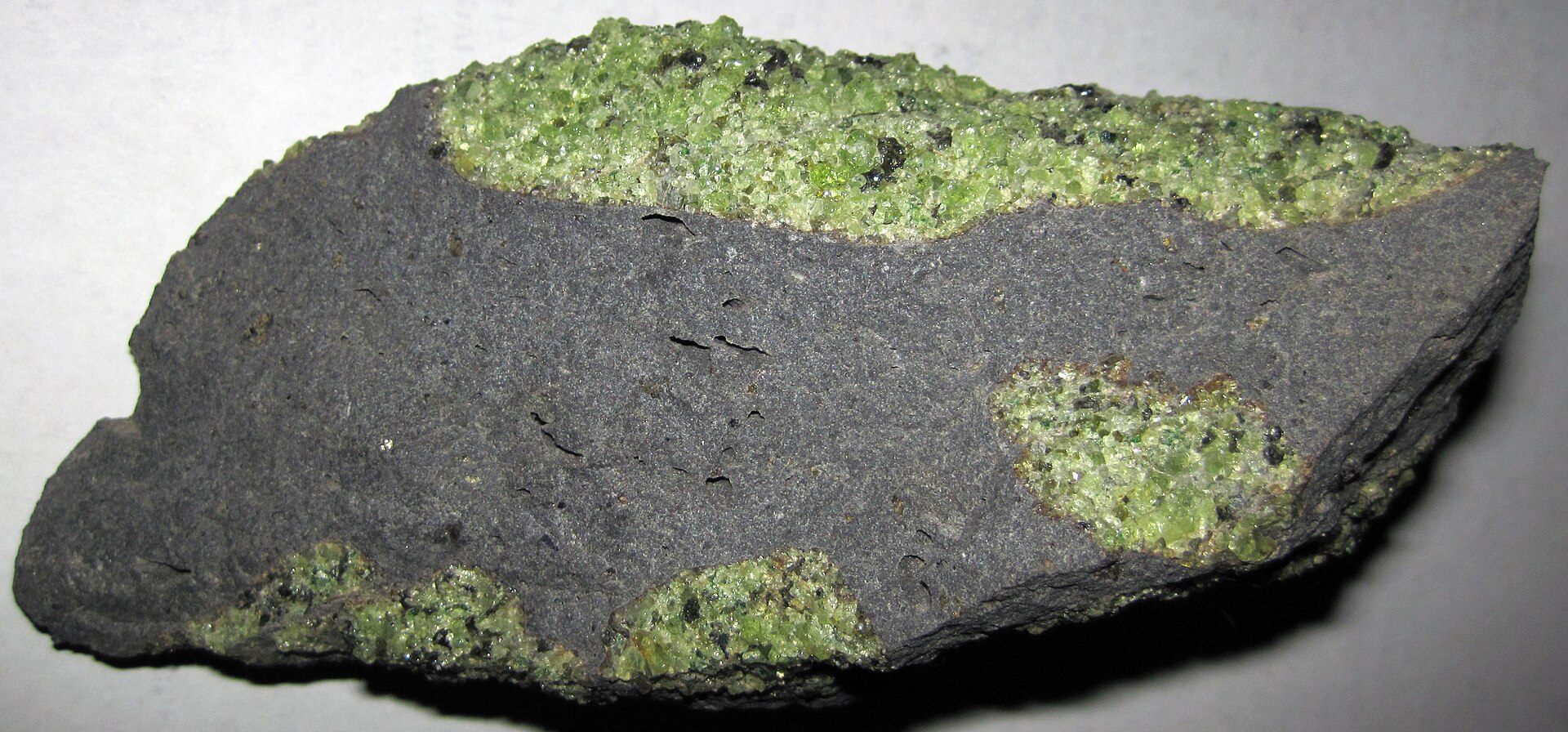 Peridot crystal mineral specimen — Peridotite mantle xenoliths in vesicular phonotephrite from the Pleistocene of Arizona, USA. Green =