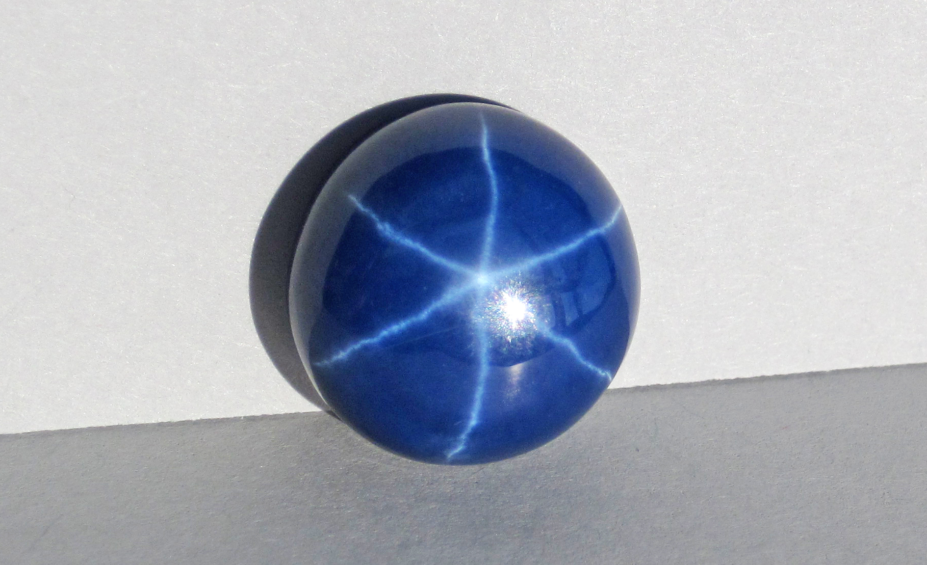 Ruby gemstone mineral specimen — (15 millimeters across at its widest) This polished cabochon ("cab") is a synthetic blue sapphire. S